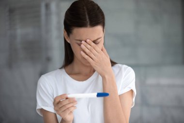 Hamilelik testine bakan üzgün kadın kötü sonuç hayal kırıklığına uğrar.