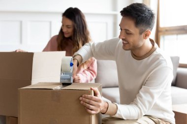 Gülümseyen koca yapışkan bantla mühürleme kutusu, taşınma günü