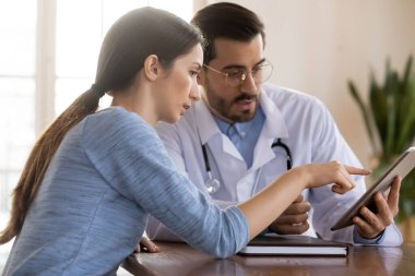 Erkek doktor hastayla tabletteki sonuçları tartıştı