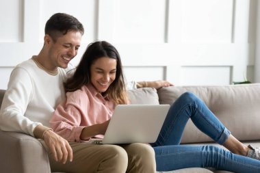 Mutlu genç çift birlikte dizüstü bilgisayar kullanıyor, hafta sonları eğleniyorlar.