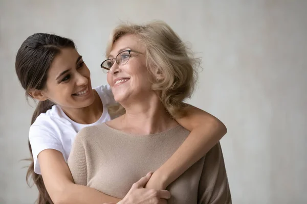 Adulto figlia abbracci da dietro felice madre matura . — Foto Stock