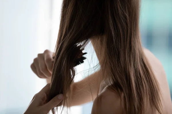 Closeup rear view woman combing hairs do morning routine — Stock Photo, Image