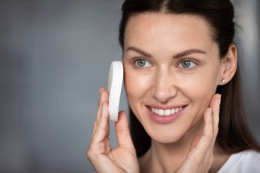 Woman cleansing skin uses facial sponge closeup face clipart