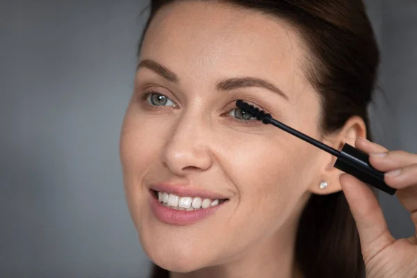 Close-up vrouwelijke gezicht holding tube van toepassing zwarte mascara — Stockfoto