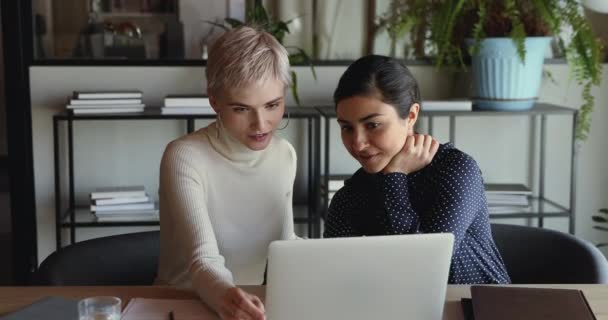 Dos diversas mujeres de negocios hablando con el ordenador portátil sentado en el lugar de trabajo — Vídeo de stock