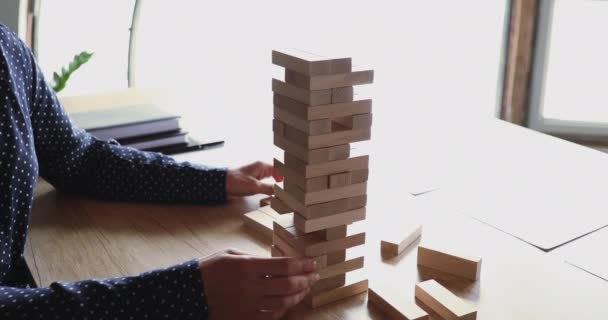 Kobieta bierze cegły z upadającej wieży Jenga. — Wideo stockowe