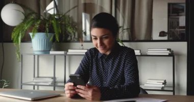 Genç, mutlu Hintli iş kadını akıllı telefona bakarken heyecanlanıyor.