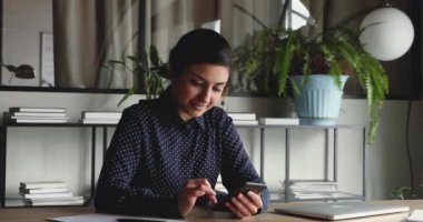 Ofiste akıllı telefon mesajı kullanan Hintli profesyonel iş kadını.
