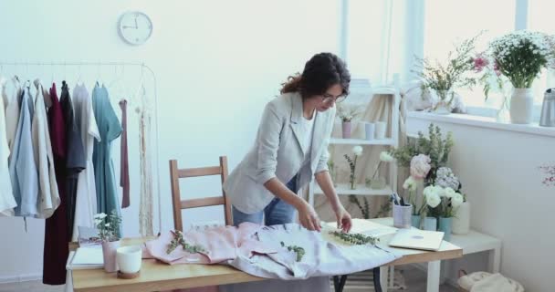 Női divattervező díszítő új egyedi ingek zöld ágak — Stock videók