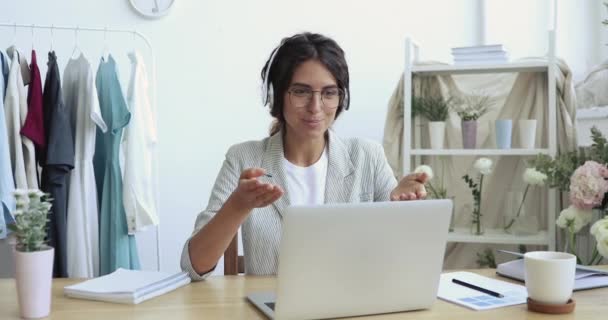 Female fashion designer wearing headphones making video call on laptop — Stock Video