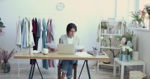 İş yerinde dizüstü bilgisayar kullanan genç moda tasarımcısı raporları analiz ediyor — Stok video