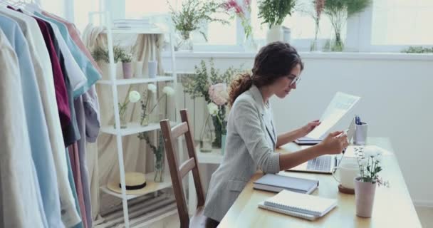 Gülümseyen milenyum moda tasarımcısı dizüstü bilgisayarını kullanarak yeni tasarım üzerinde çalışıyor — Stok video