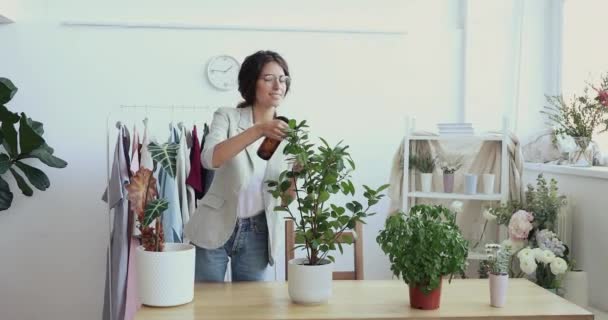 Diseñador de moda cuidando las plantas rociando hojas en la oficina — Vídeo de stock