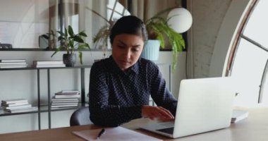 Ciddi bir Hintli işçi ofis masasında dizüstü bilgisayar kullanıyor.