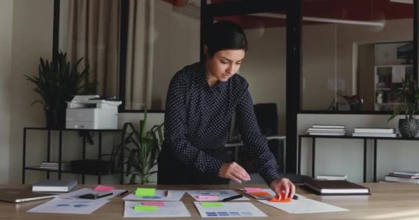 Konzentrierte indische Angestellte, die im Büro arbeitet und Aufkleber auf Papier klebt — Stockvideo