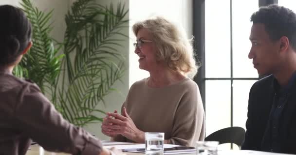 Sonriente anciana mayor empleada hablando con diversos colegas jóvenes . — Vídeo de stock