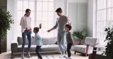 Anaokulu çocuklarıyla müzik eşliğinde dans eden neşeli genç ebeveynler..