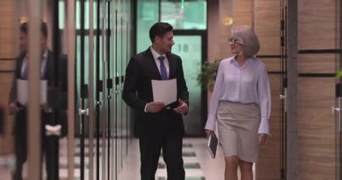 Kendine güvenen bir erkek yönetici, 60 'ların kadın lideriyle koridorda yürüyor..