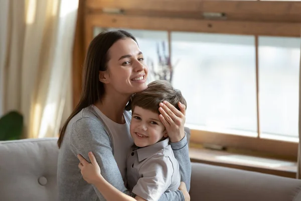 Feliz joven mamá y su pequeño hijo abrazándose en casa — Foto de Stock