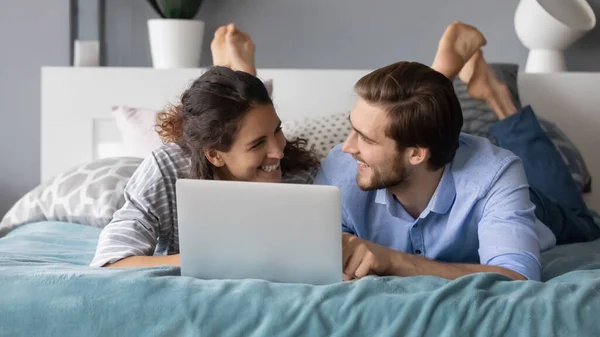 Sorrindo casal relaxar na cama usando laptop juntos — Fotografia de Stock