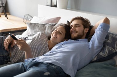 Genç çift yatakta birlikte televizyon seyrediyor.
