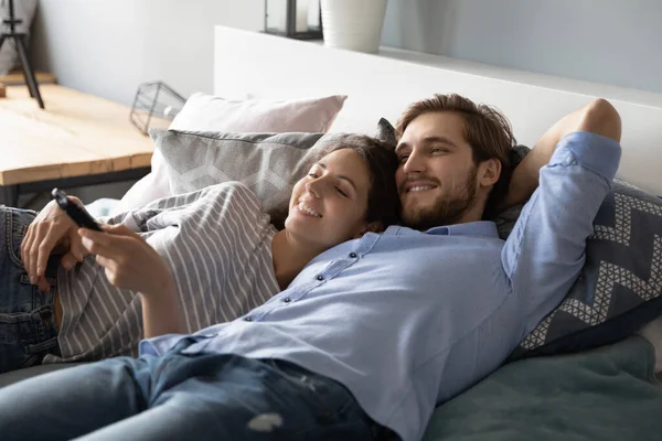 Junges Paar liegt gemeinsam vor dem Fernseher im Bett — Stockfoto