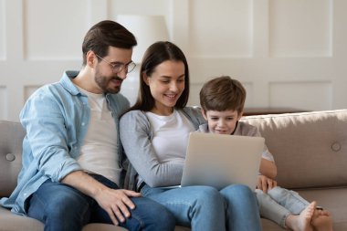 Evde dizüstü bilgisayar kullanan küçük oğlu olan genç bir aile.