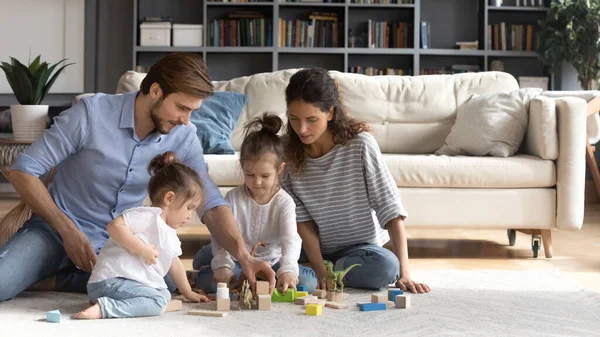 Молодая семья с маленькими детьми играет дома — стоковое фото