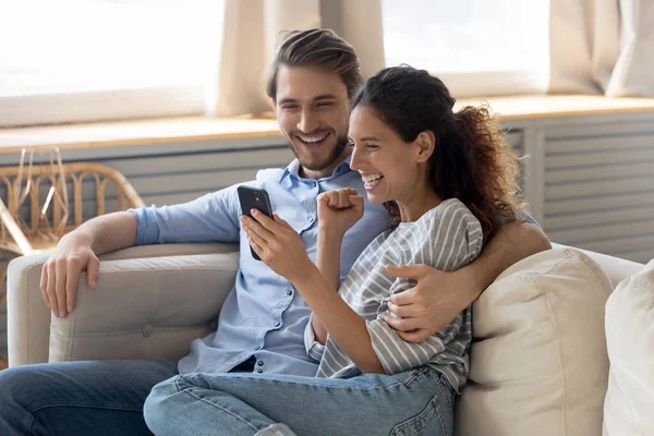 Aufgeregtes Paar triumphiert beim Lesen guter Nachrichten auf dem Smartphone — Stockfoto