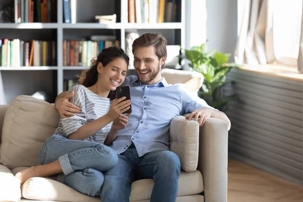 Mutlu genç çift evde akıllı telefon kullanıyor. — Stok fotoğraf