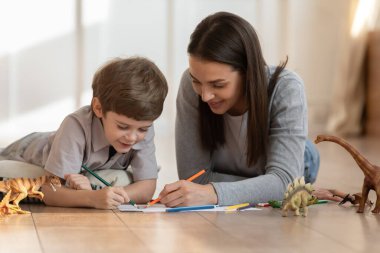 Genç anne ve küçük oğlu birlikte resim yapıyorlar.