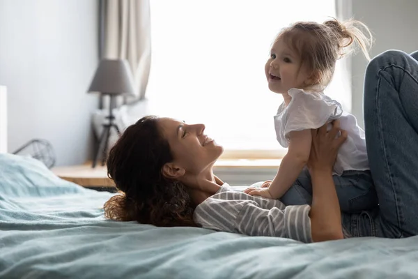 Happy young mom relax in bedroom with little daughter — Stock Photo, Image