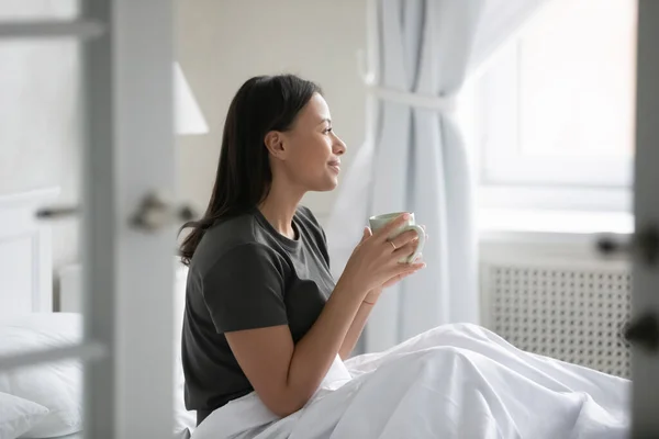 African woman wakeup sitting in bed drinking morning coffee — Stock Photo, Image