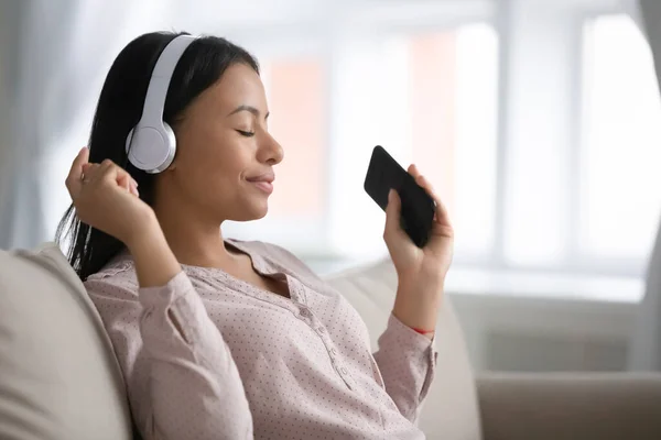 Afrikaanse vrouw het dragen van draadloze hoofdtelefoon met behulp van smartphone playlist luistert muziek — Stockfoto