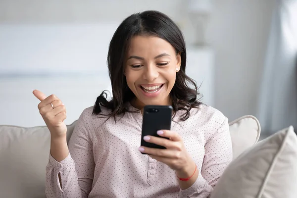 African female holds smartphone feels overjoyed showing thumbs up — Stock Photo, Image