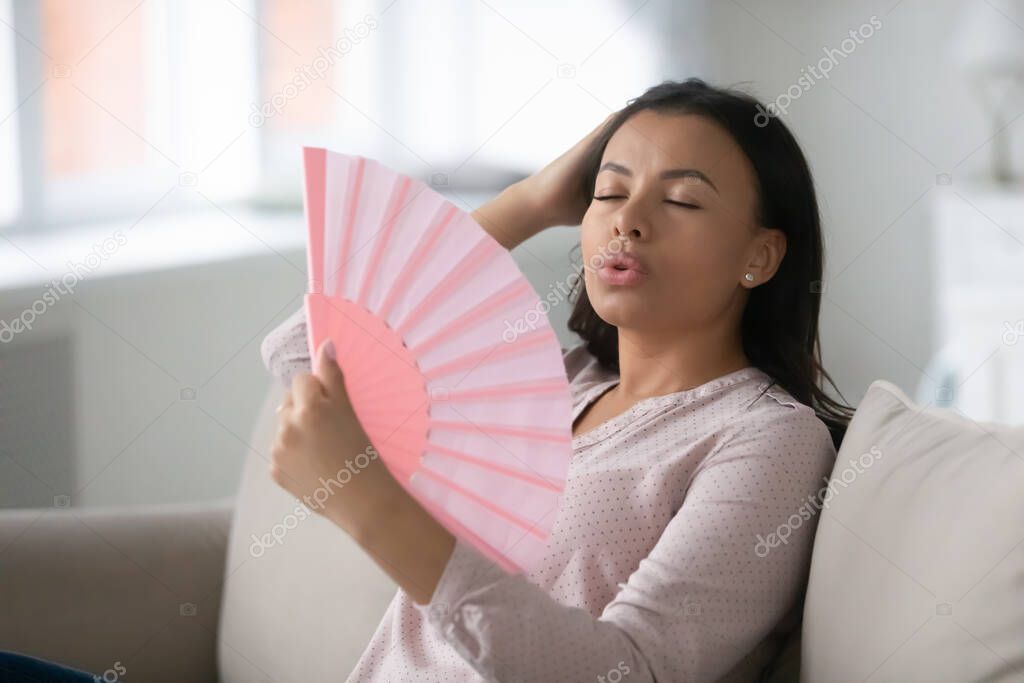 Overheated African woman escapes from heat with fan feels unwell