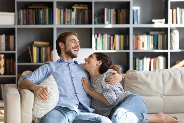 Щаслива молода пара відпочиває на дивані сміється — стокове фото
