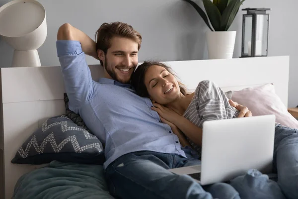 Kafkasyalı mutlu çift dizüstü bilgisayar kullanarak yatakta rahatlıyor. — Stok fotoğraf