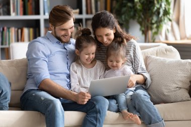 Evde dizüstü bilgisayar kullanan mutlu bir aile.