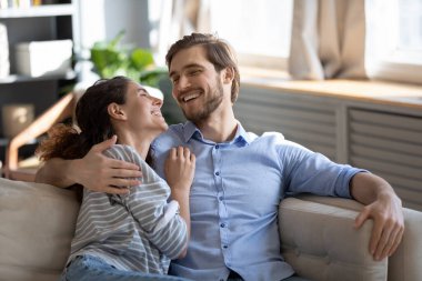 Gülümseyen çift evdeki kanepede sarılıp dinleniyor.