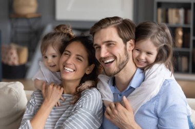 Küçük çocuklu mutlu aile evde sarılıyor.