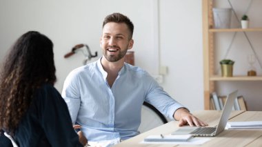 Gülen işadamı, toplantı odasında dizüstü bilgisayar kullanarak iş kadınıyla konuşuyor..