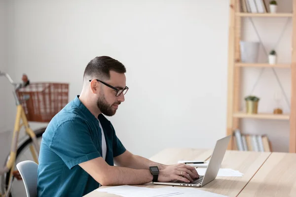 Side view knappe jonge zakenman typen op toetsenbord met behulp van laptop. — Stockfoto