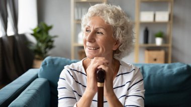 Mutlu engelli büyükanne elinde bastonla evde dinleniyor..