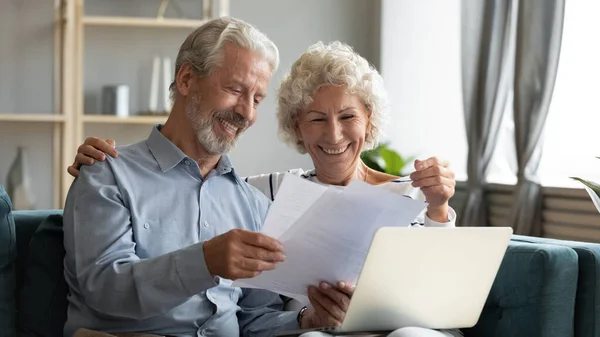 Pareja de familia de mediana edad feliz mirando a través de documentos en papel . — Foto de Stock