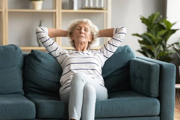 穏やかな穏やかな成熟したシニア女性napping一人で快適なソファ. — ストック写真