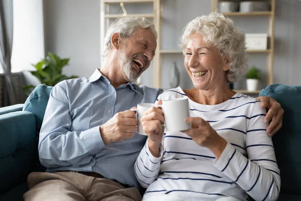 Alegre pareja de la familia madura riendo de chistes, beber café de la mañana . — Foto de Stock