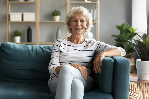 Щаслива бабуся середнього віку розслабляється на дивані . — стокове фото