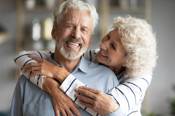 Loving middle aged married couple spending time together at home.