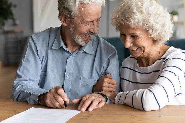 Sonriente mujer hombre de mediana edad poniendo firma en el contrato de matrimonio . — Foto de Stock